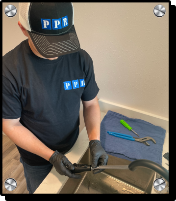 a plumber wearing a hat with the ppr logo is installing a new black sink faucet